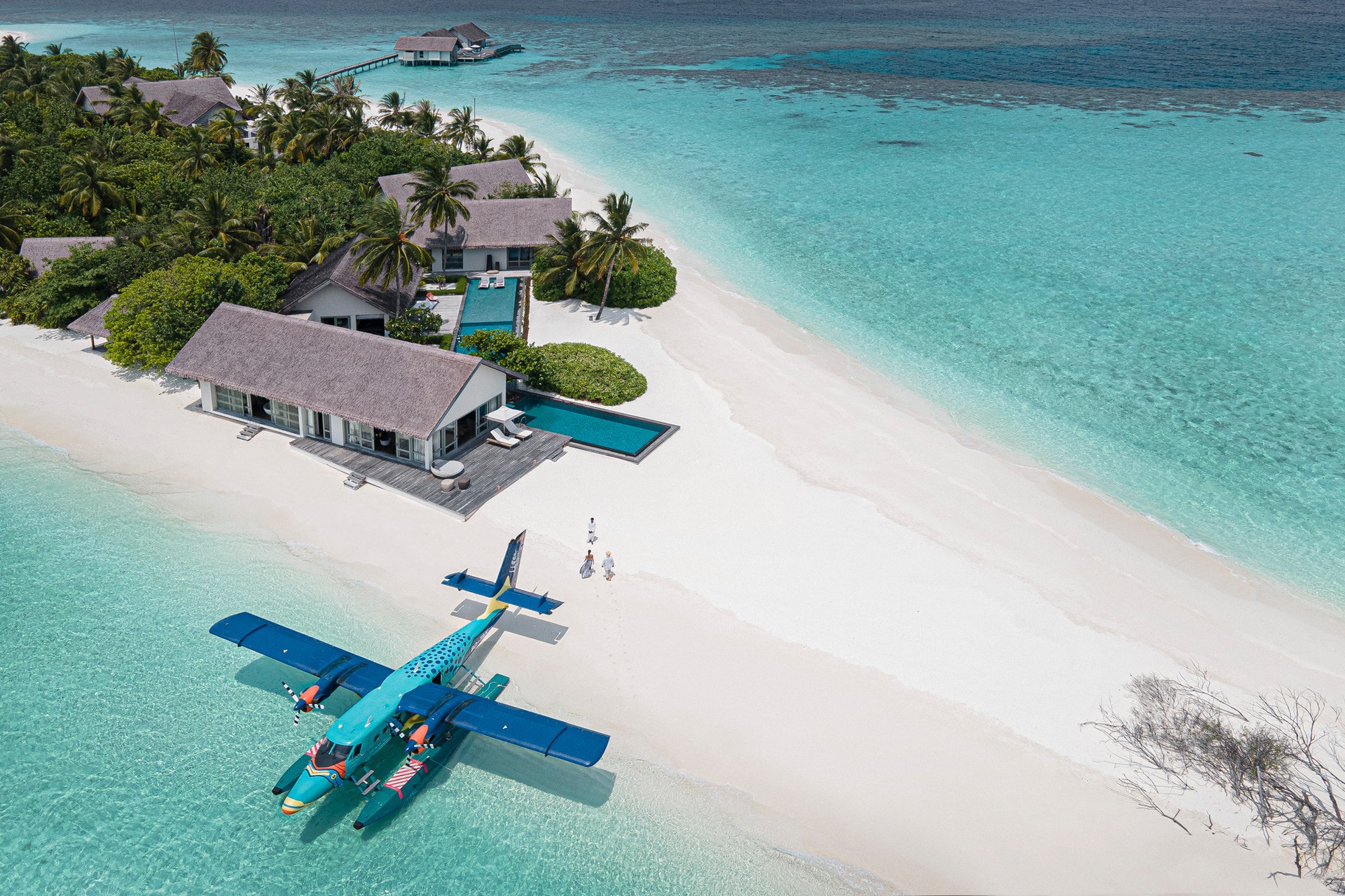 Aerial view of luxury Maldives beach villa with private pool and seaplane on turquoise lagoon