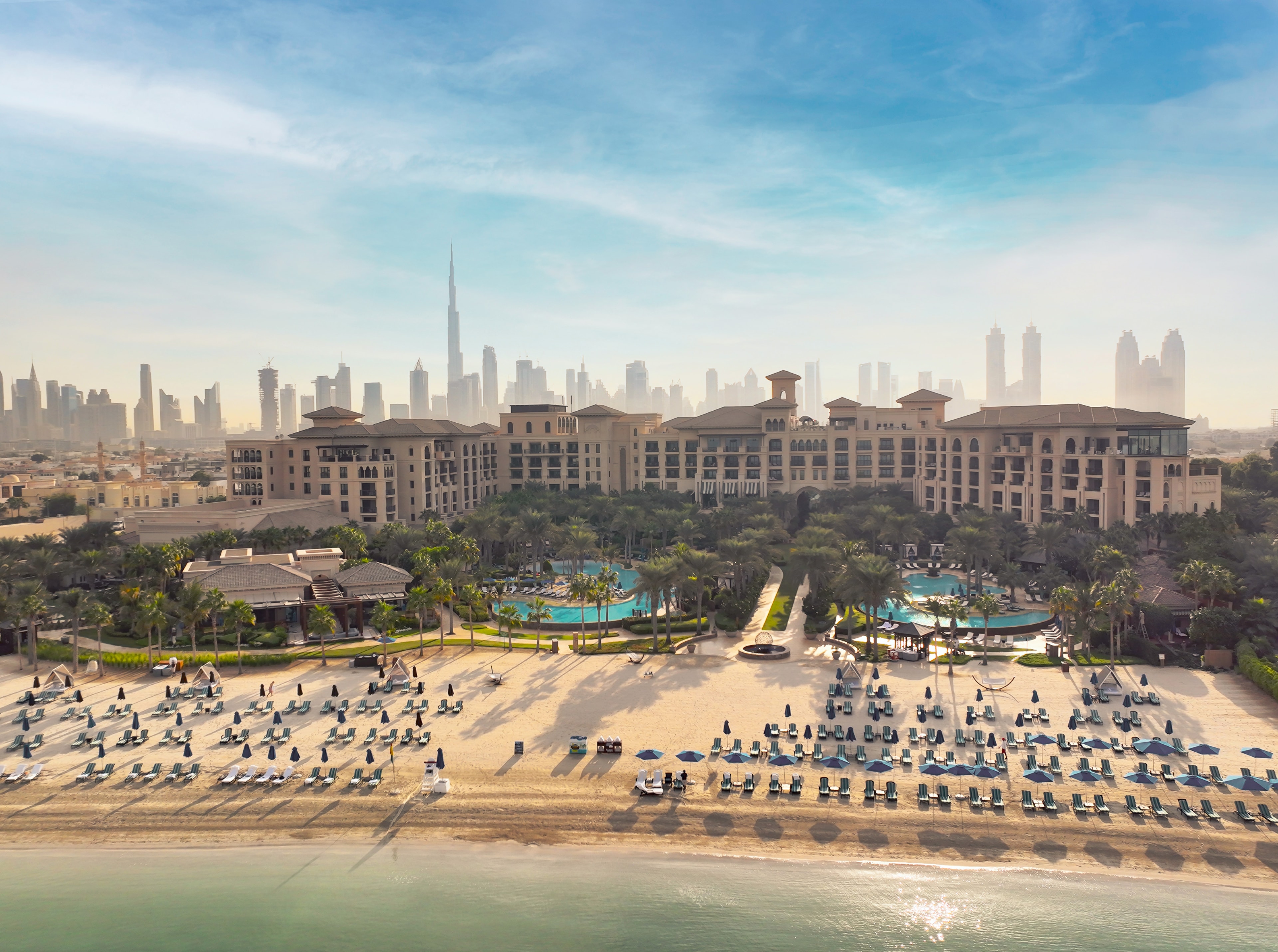 Luxury beachfront resort aerial view with pools and Dubai skyline